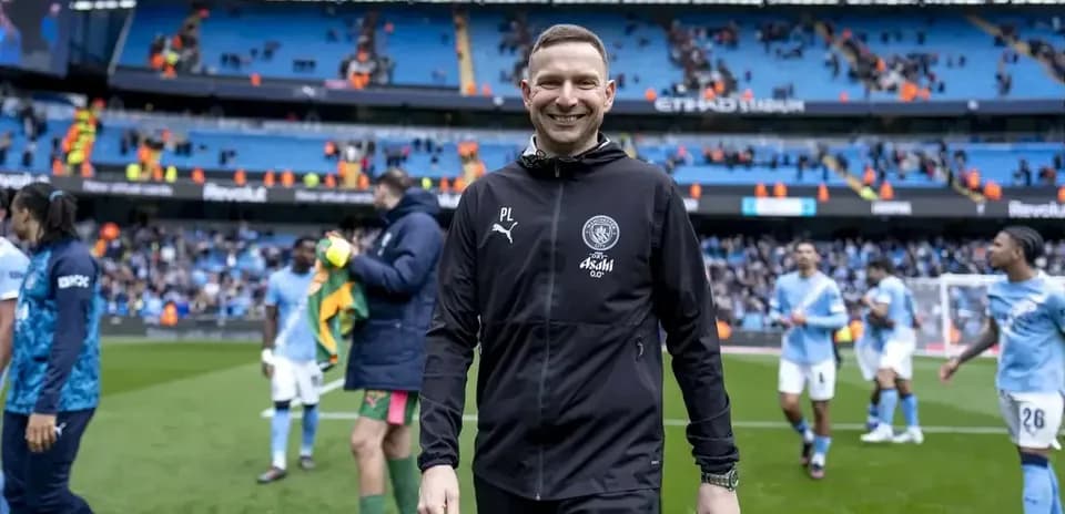 Entrenador sonriendo en el campo tras el partido