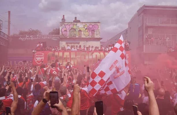 Aficionados celebrando con humo y banderas de Arsenal