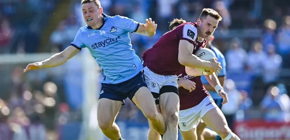 Jugador de Galway avanzando mientras es defendido por Dublín