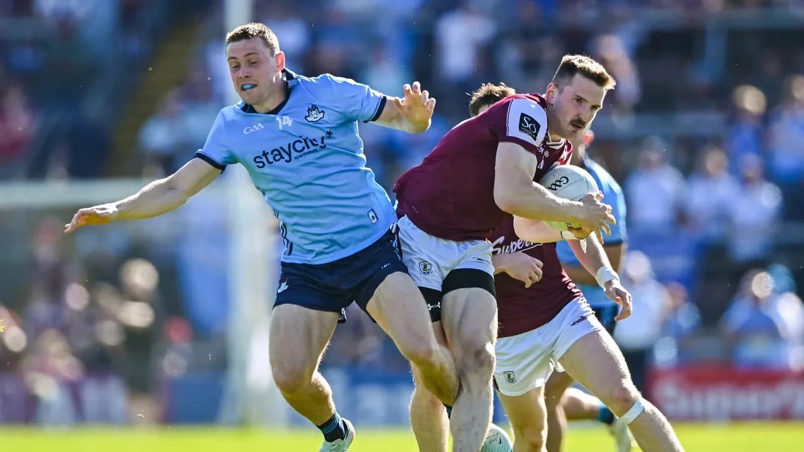 Jugador de Galway avanzando mientras es defendido por Dublín