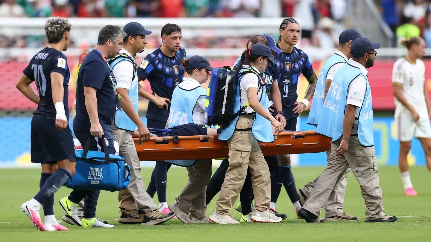 Jugadores observando mientras llevan a un jugador en camilla