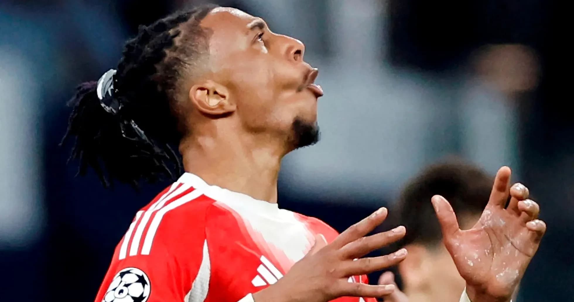 Jugador con camiseta roja mirando hacia arriba en el campo