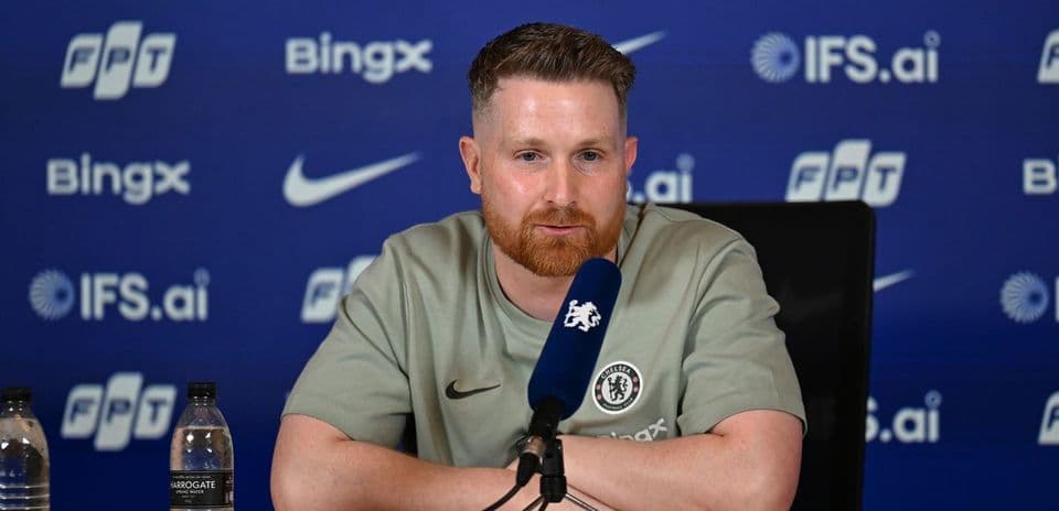Entrenador en conferencia de prensa con logotipo de Chelsea