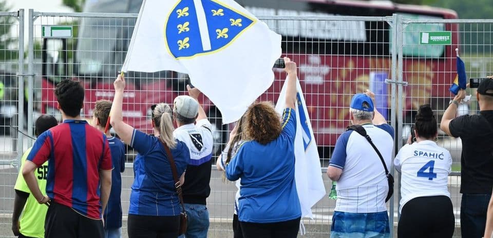 Aficionados sosteniendo banderas de Bosnia