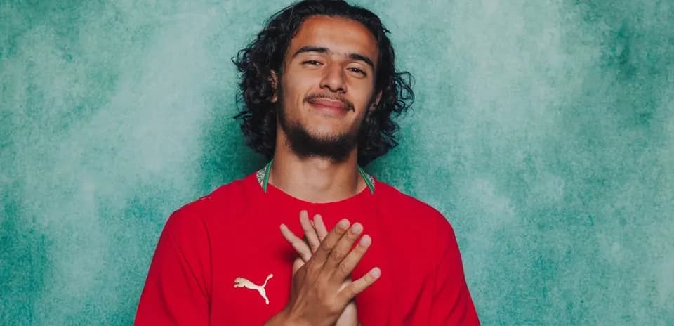 Jugador con camiseta roja sonriendo y manos juntas