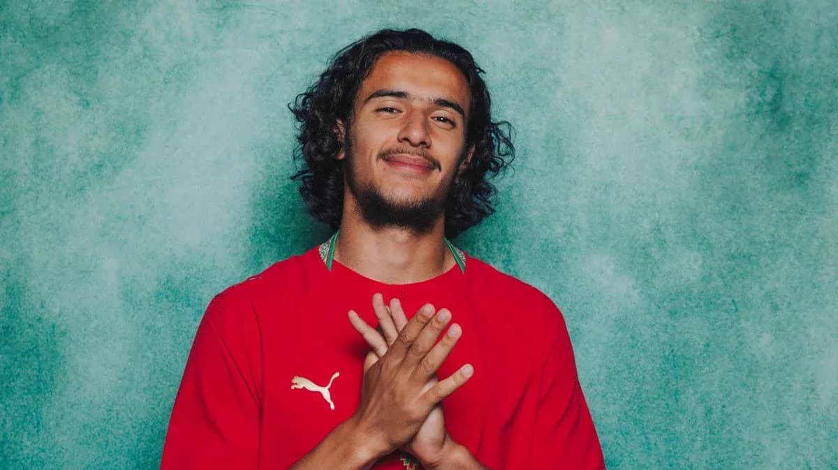 Jugador con camiseta roja sonriendo y manos juntas