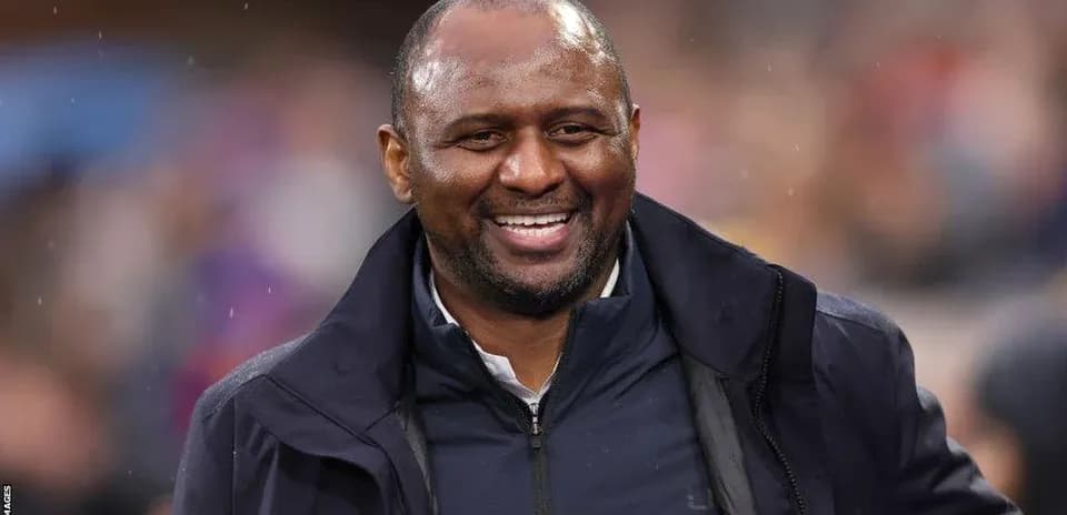 Entrenador sonriendo en el banquillo durante el partido
