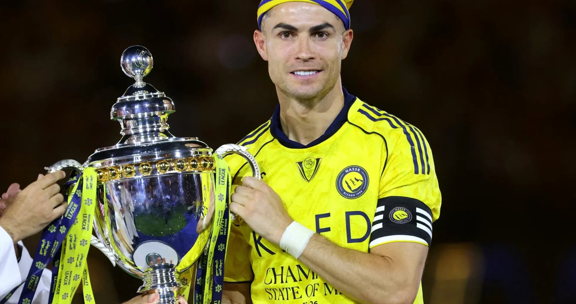 Jugador sosteniendo trofeo con camiseta de Al Nassr