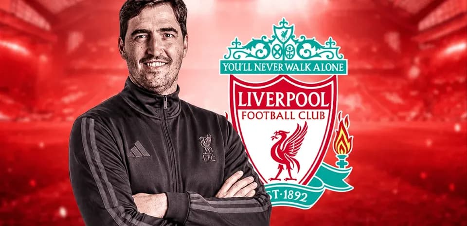 Entrenador sonriendo frente al logo de Liverpool