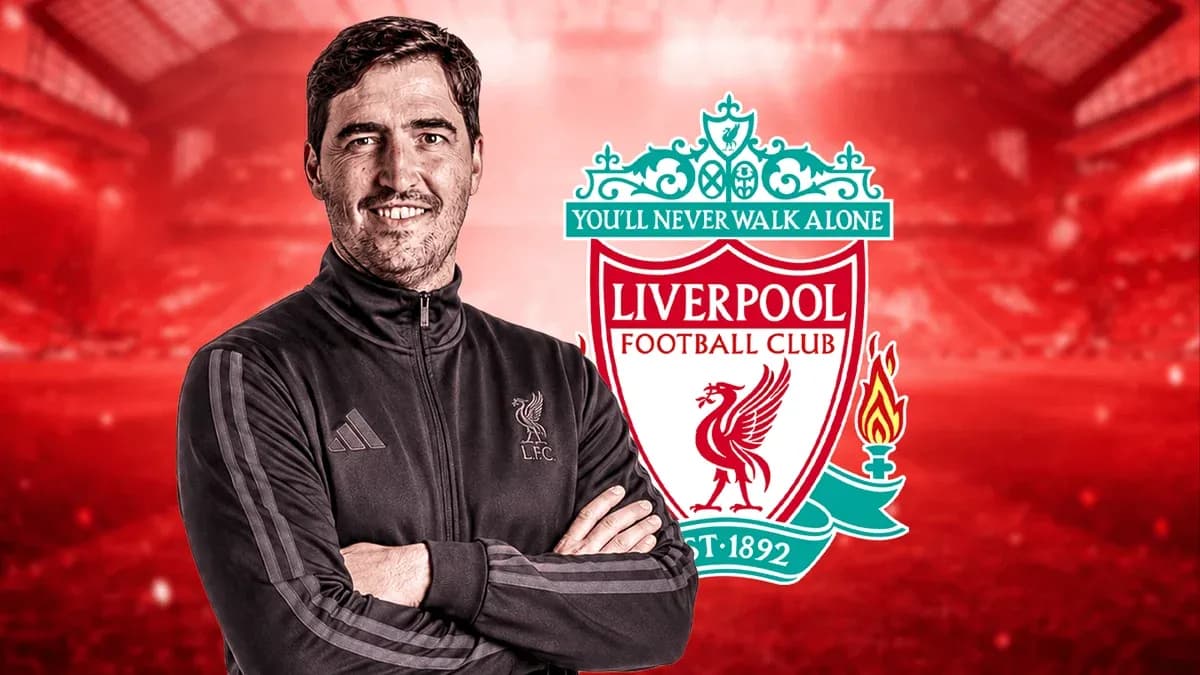 Entrenador sonriendo frente al logo de Liverpool