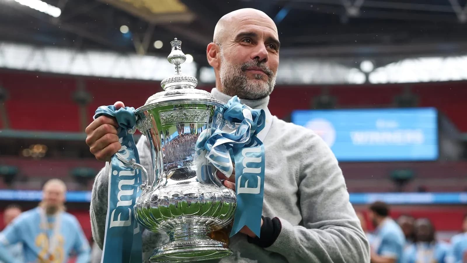 Entrenador sosteniendo trofeo en el estadio Wembley
