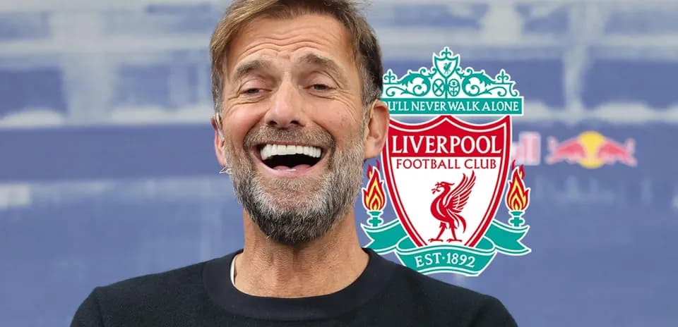 Entrenador sonriente con logo de Liverpool detrás