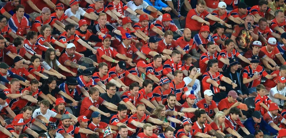 Aficionados en la grada animando en uniforme rojo