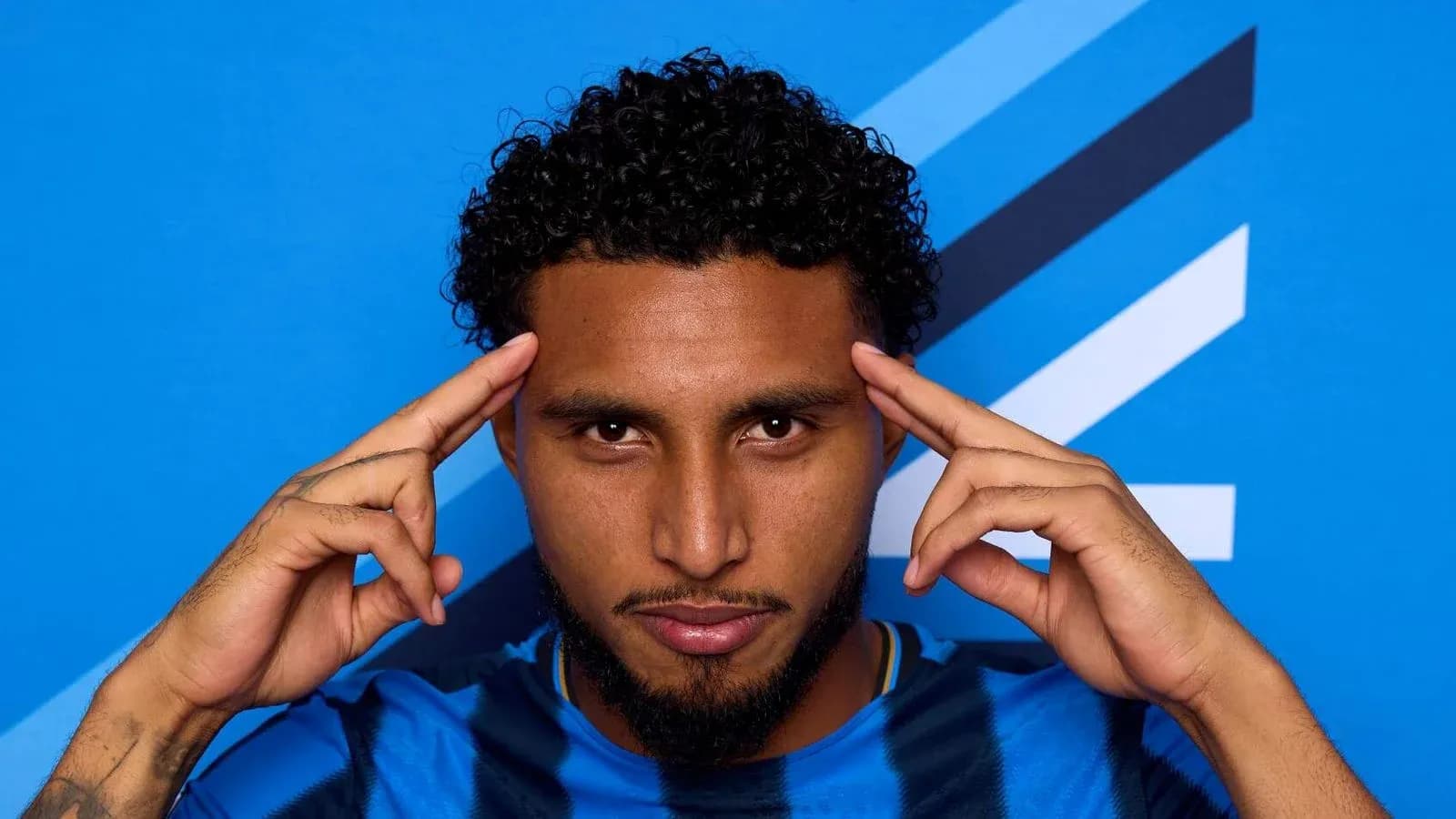 Jugador posando con fondo azul y camiseta rayada