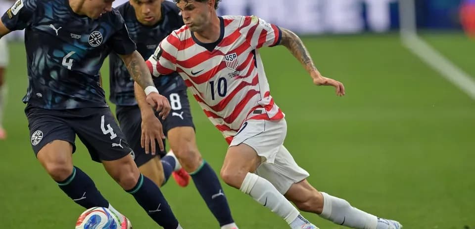 Christian Pulisic dribbling past Paraguayan defender