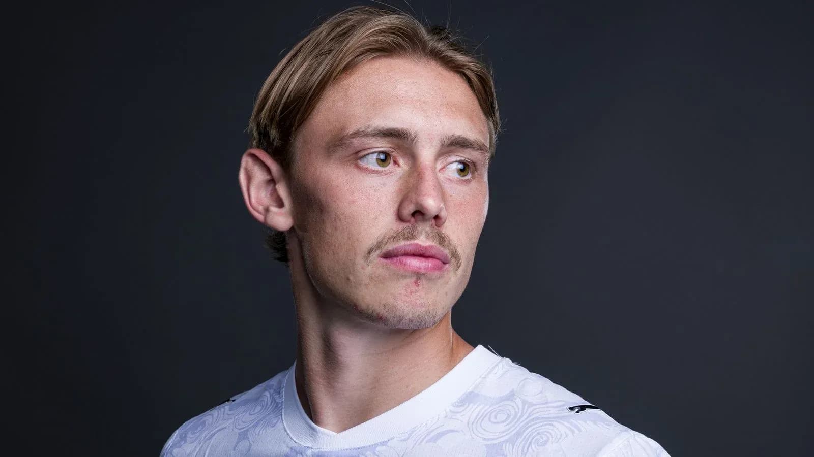 Jugador posando con camiseta blanca y fondo oscuro