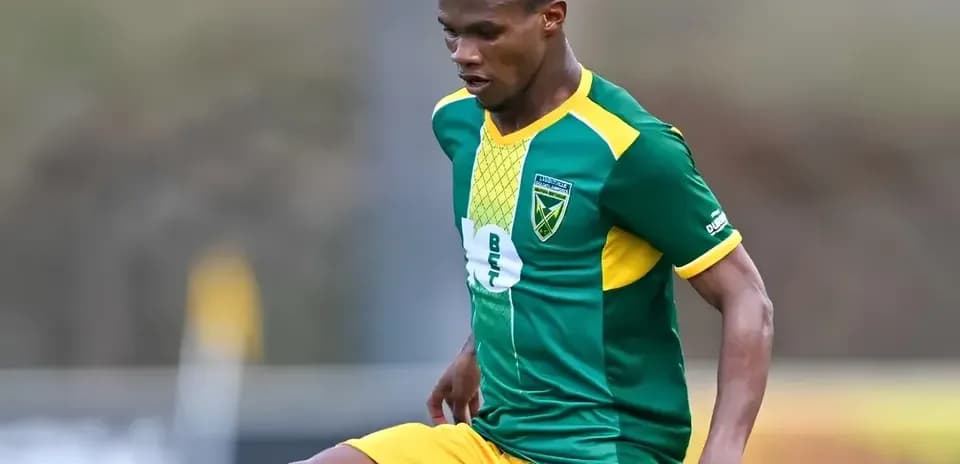 Jugador de fútbol en acción con camiseta verde y amarilla