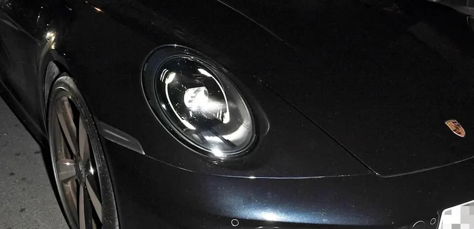 Dos hombres dentro de un Porsche negro en la calle