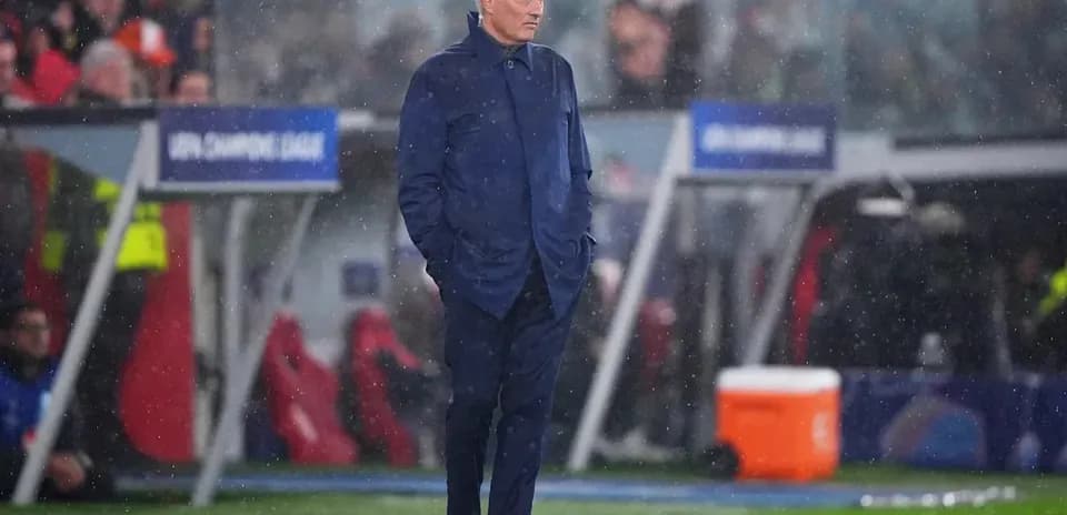 Entrenador en el banquillo durante un partido lluvioso