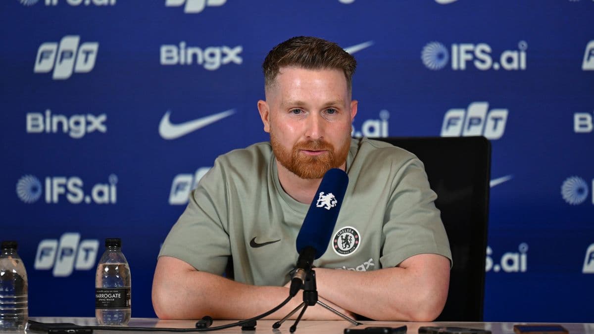 Entrenador en conferencia de prensa con logotipo de Chelsea Entrenador en conferencia de prensa con logotipo de Chelsea